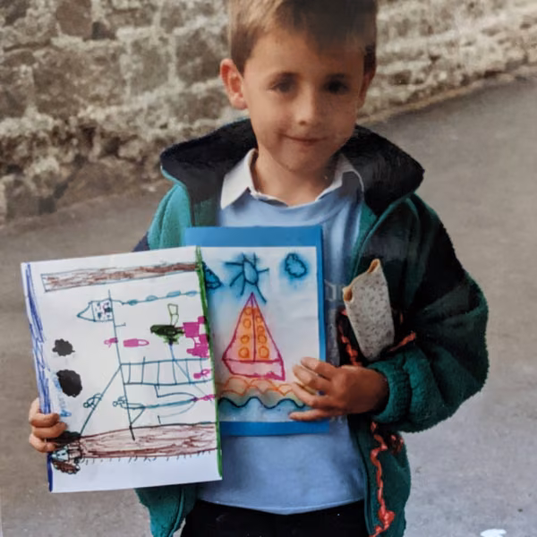 A boy holding up two drawings